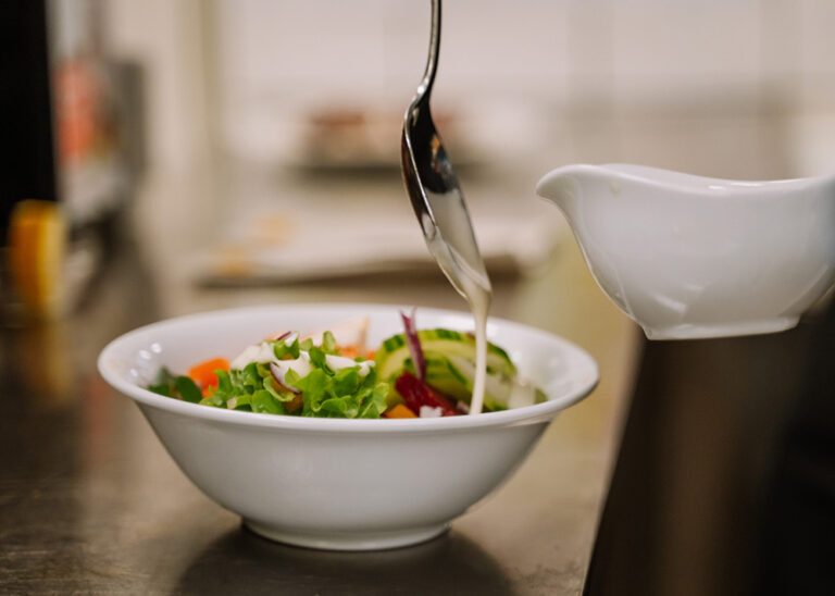 Vegane Salatschüssel wird mit frisch zubereitetem Dressing verfeinert